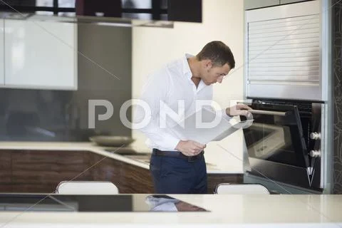 Mid Adult Man Inspecting Oven In Kitchen Showroom