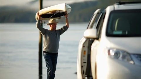 Mid adult man loading paddleboard onto truck. Video stock 88407445
