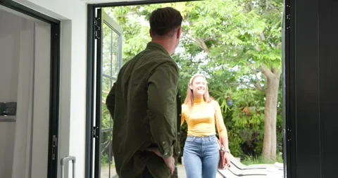 Mid-adult man pulling silver suitcase across patio and leading family through Stock Footage 317078105