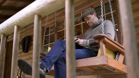 Mid adult man taking notes while sitting on a swing bed Stock Footage 77081145