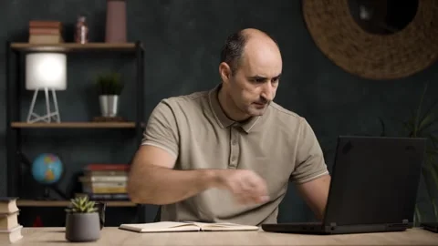 Mid Adult Man Taking Notes in Notebook While Working on Laptop at Home Stock Footage 342236725