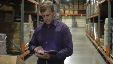 Mid adult man using a tablet in a warehouse 動画素材 83395808