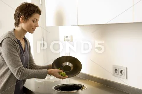Mid Adult Woman Scraping Vegetables Pieces Into A Garbage Bin