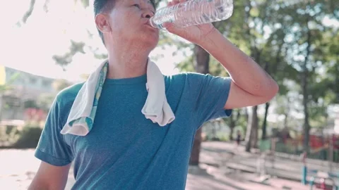 Mid age asian man drinking fresh cold water from plastic bottle after exercise Video stock 144165642