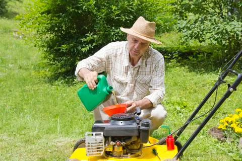 Mid age man adding oil to lawn mover Stock Photos
