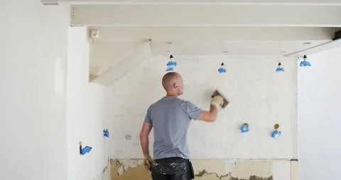 Mid-age man renovating Plaster application on old wall Renovation tutorial: Stock Footage 246554194