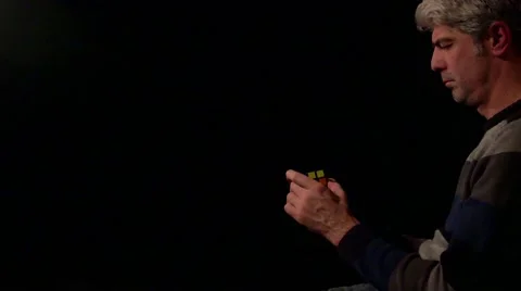 A mid age man solving a Rubik´s cube isolated on a black background Stock Footage 63212219
