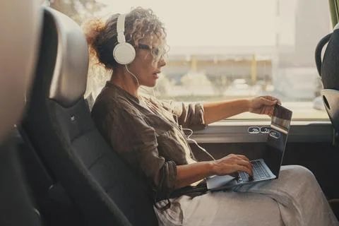 Mid age woman using computer inside transport bus vehicle during business o.. Fotos de archivo