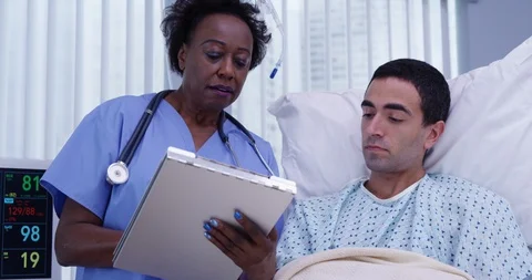 Mid aged African doctor explaining to young patient the medical procedure Video stock 94838210