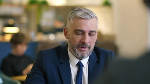 Mid-Aged Businessman Explaining Project Details to Partner at Meeting in Cafe Stock Footage 315681382
