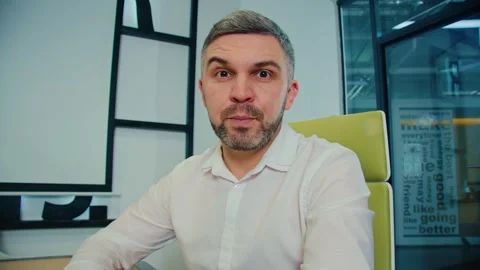 Mid aged businessman talking to camera at online meeting while sitting in office Stockbeeldmateriaal 244740924