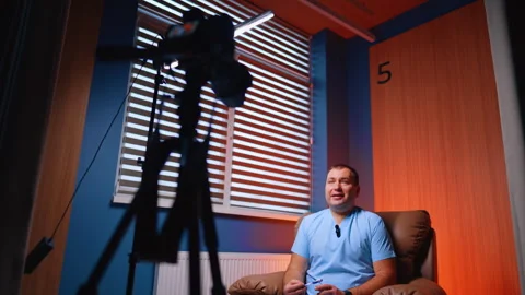 Mid-aged Caucasian man in blue uniform sits in front of camera. Low angle view. Stock Footage 333782631