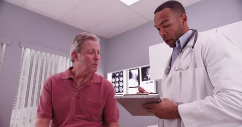 Mid aged caucasian patient consulting with a young intelligent african doctor Stock Footage 60982543