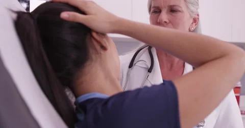 Mid aged doctor checking soccer player's sports head injury Stock Footage