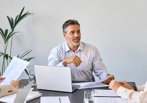 Mid aged Latin business man ceo manager boss leading team meeting in office. Stock Photos