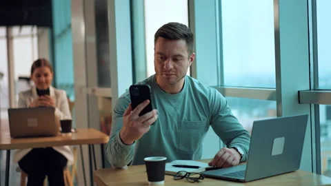 Mid-aged man checking information on the phone and paper notebook Stockbeeldmateriaal 223984768