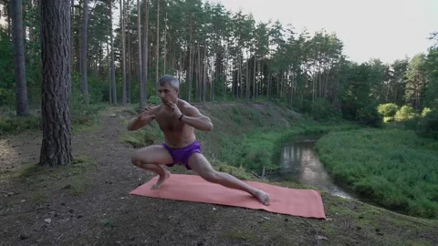 Mid aged man does exercises on mat on edge of cliff Stock Footage 168002988