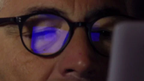 Mid aged man with glasses with blue reflection of the screen of the phone Stock Footage 74430054