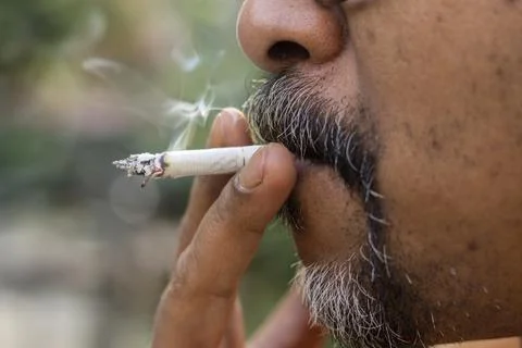 A mid aged man smoking a cigarette with selective focus Stock Photos