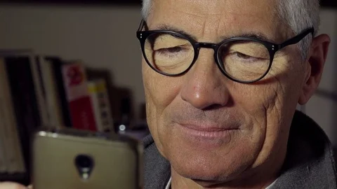 Mid aged man surf on internet: read news and messages with smartphone at home Stock Footage 74431127