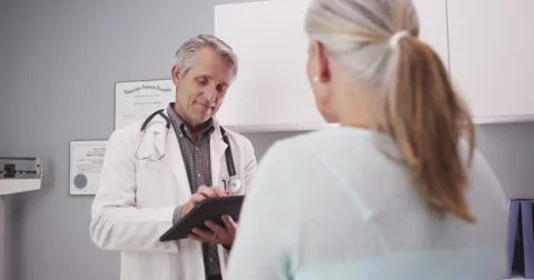 Mid-aged medical doctor consulting a patient with tablet Stock Footage