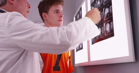 Mid aged physician looking at brain xrays with sports athlete patient Stock-Footage 60968747