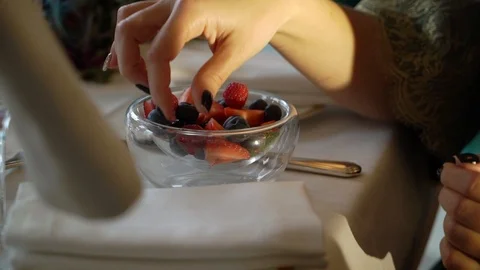 Mid-aged woman taking raspberry from plate Stock Footage 102787898