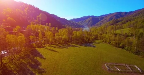 Mid air flight over fresh mountain river and meadow at sunny summer morning Stock Footage