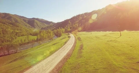 Mid air flight over fresh mountain river and meadow at sunny summer morning Stock Footage