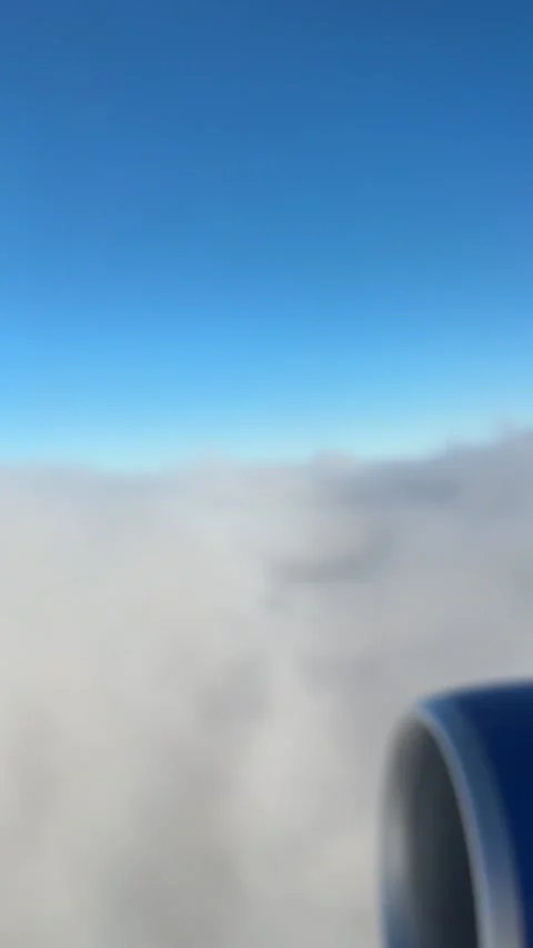 Mid-Air view of airplane engine flying over clouds with a blue sky 動画素材 335481016