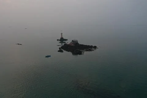 Mid-Altitude View of Lighthouse Islet and Rocky Sea in Morning Mist Stock Photos