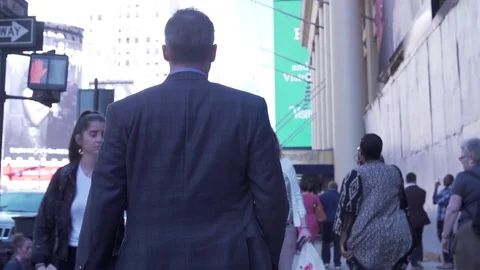 Mid angle view of businessman walking through streets of midtown Manhattan with Vidéo 83550723