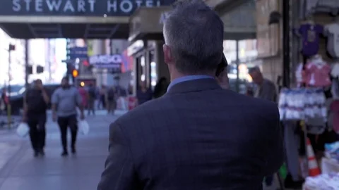 Mid angle view of businessman walking through streets of midtown Manhattan with Stock Footage 83550739