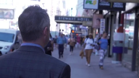 Mid angle view of businessman walking through streets of midtown Manhattan with Stock Footage 83550742