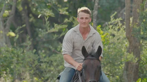 Mid to close up shot of man cantering a horse along a dusty track Stock Footage 135282221