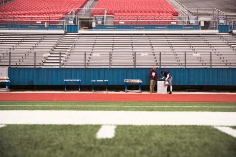 Mid distance view of Coach and American football player at stadium Stock Photos