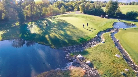Mid height circle players on green near pond Stock Footage 105606595