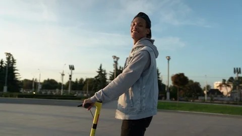 Mid profile shot: Multi-ethnic guy ride electric scooter with pleasure and smile Stock Footage 115986733