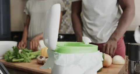 Mid section of african american couple throwing food waste out in ktichen in Stock Footage 340068411