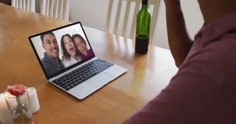 Mid section of african american man drinking wine while having a video call on Stock Footage 154334548