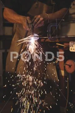 Mid Section Of Blacksmith Working At Work Shop