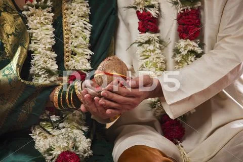 Mid Section Of Bride And Groom Holding Coconut Together