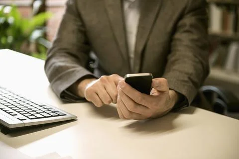 Mid section of a businessman using smart phone in an office, Bavaria, Germany Stock Photos