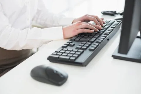 Mid section of businesswoman using computer keyboard in office Fotos de archivo