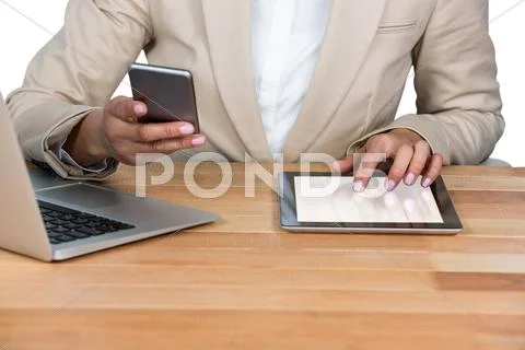 Mid-Section Of Businesswoman Using Mobile Phone And Digital Tablet With Lapto