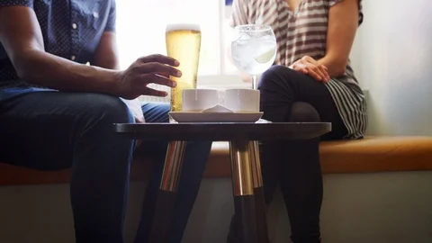 Mid section close up of couple in conversation, sitting with drinks at a window Stock Footage 99753781