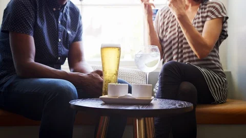 Mid section close up of couple in conversation, sitting with drinks at a window Stock Footage 99762077