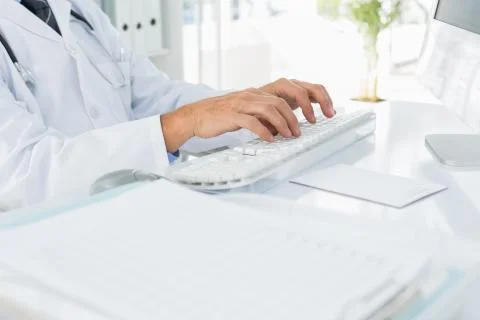 Mid section of doctor using computer keyboard at medical office Fotos de archivo