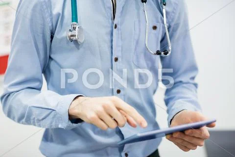 Mid-Section Of Doctor Using Digital Tablet