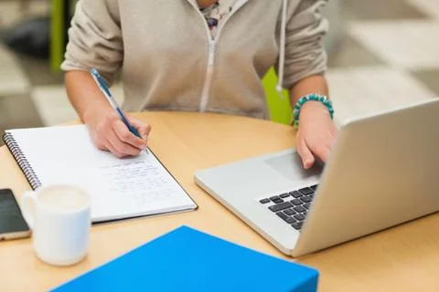Mid section of a female student doing homework by laptop Stock Photos
